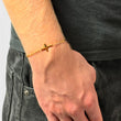 Kreuz Armband in Gold am Handgelenk, Hand in der Hosentasche
