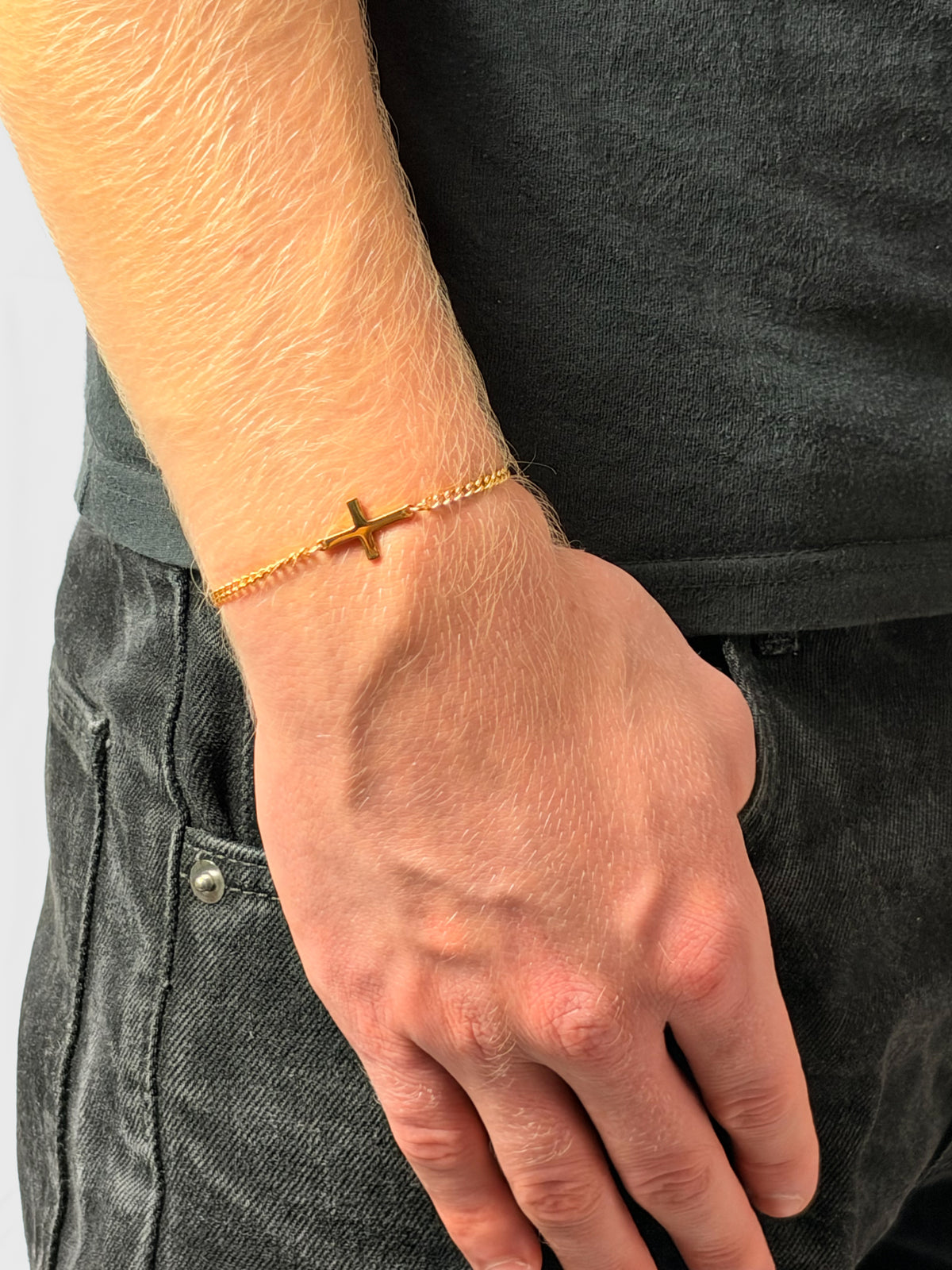 Kreuz Armband in Gold am Handgelenk, Hand in der Hosentasche