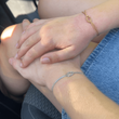 Zwei Hände mit Liebesknoten Armbändern auf dem Schoß