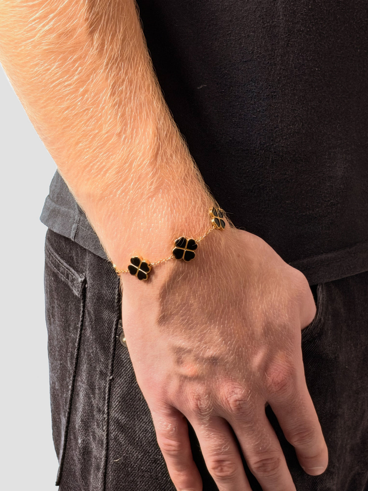 Kleeblatt Armband in Schwarz am Handgelenk, Hand in der Hosentasche