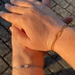 Zwei Hände übereinander mit Liebesknoten Armbändern in Gold und Silber